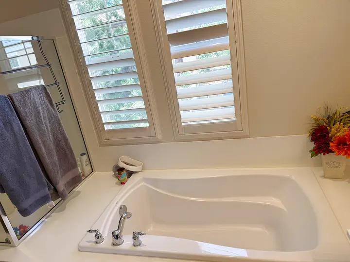 Bathroom with a polished tub and clean shutters